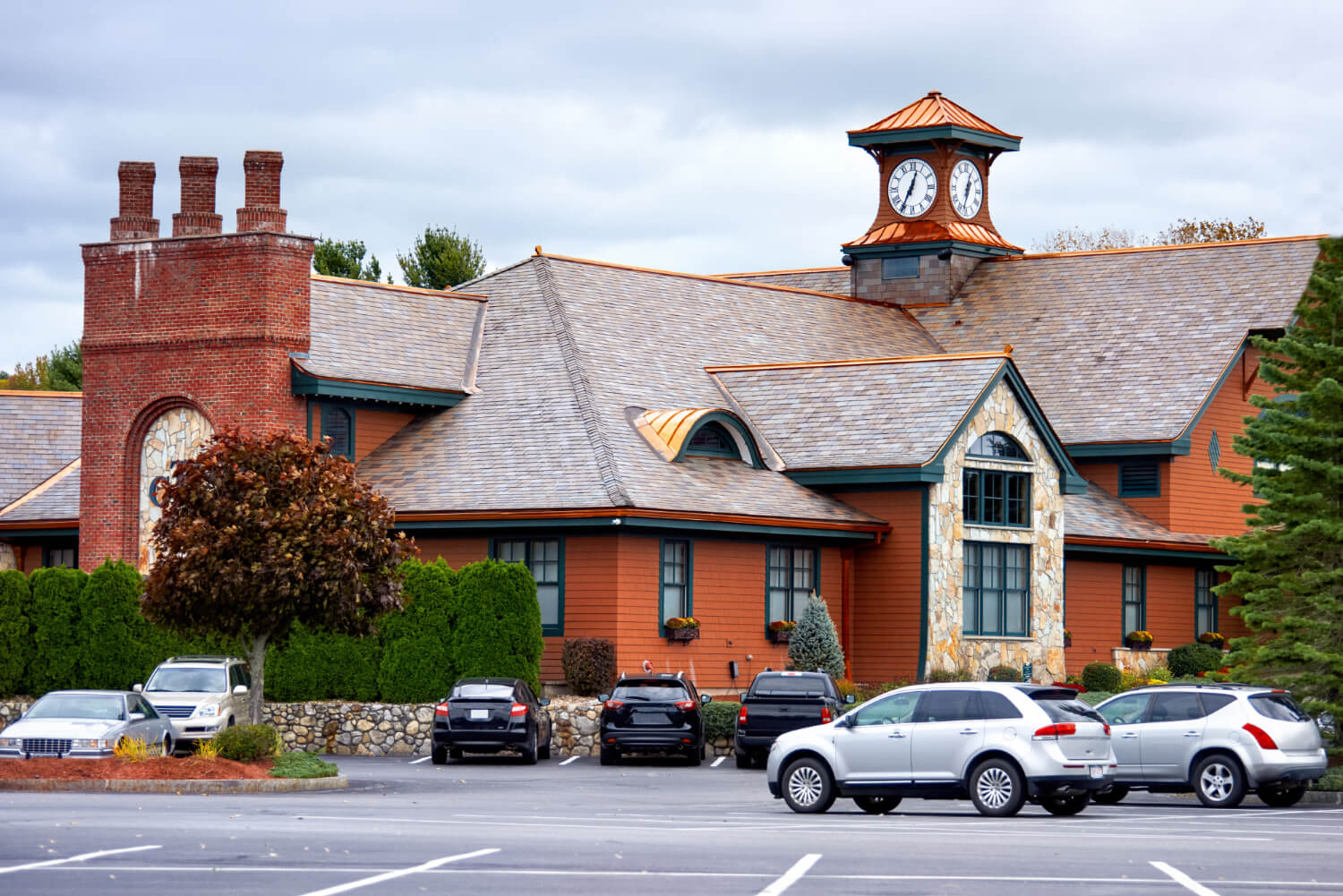 Gutter Services FAQ Red brick and wood building with clock tower and parked cars.