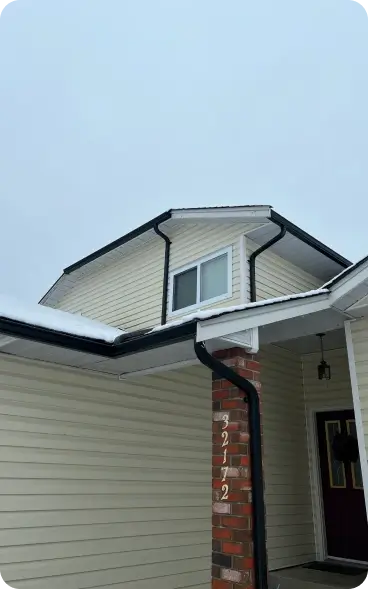 House with black gutters and snow on the roof.